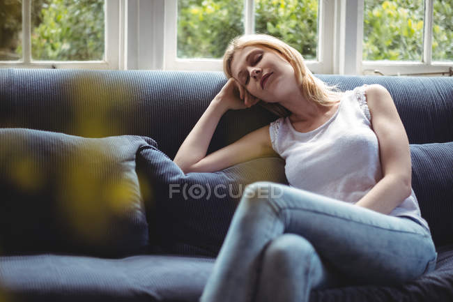 Mulher bonita relaxando no sofá na sala de estar em casa — Fotografia de Stock