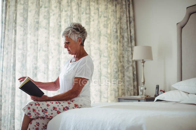 Mulher sênior lendo livro no quarto em casa — Fotografia de Stock
