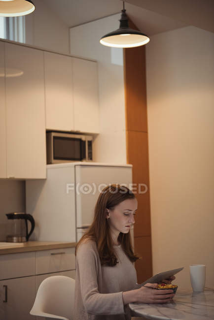 Жінка, використовуючи цифровий планшет і сніданку кухні в домашніх умовах — стокове фото
