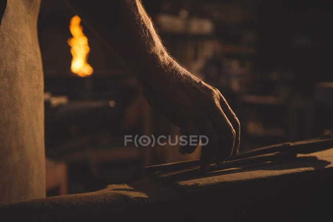 Main de forgeron tenant la pince dans l'atelier — Photo de stock