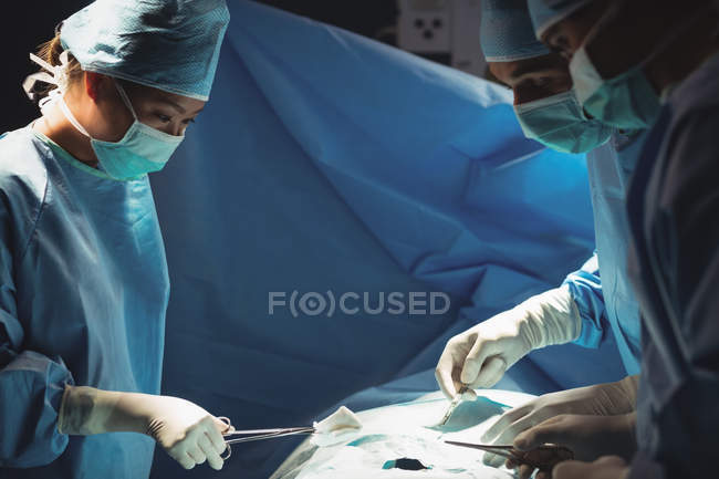 Équipe de chirurgiens effectuant une opération en salle d'opération à l'hôpital — Photo de stock