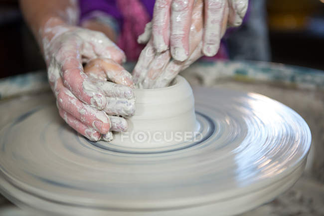 Primo piano della ragazza che assiste il vasaio nel laboratorio di ceramica — Foto stock