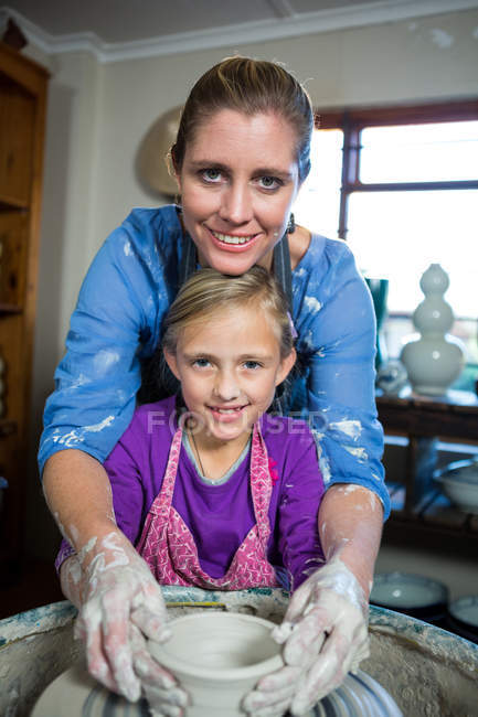 Портрет женщины-гончара, помогающей девушке в мастерской по керамике — стоковое фото