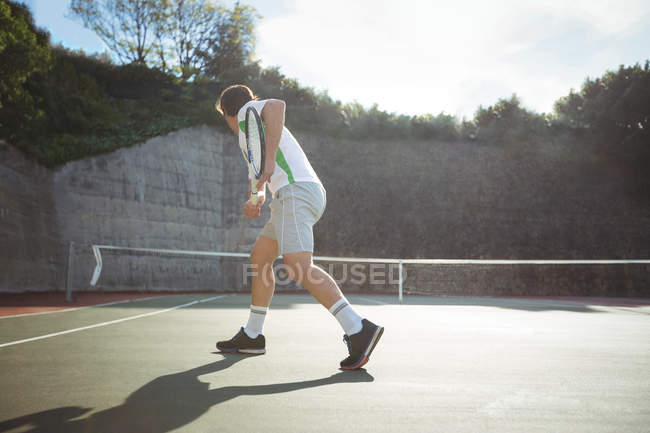 Вид сзади на человека, играющего в теннис на спортивном корте — стоковое фото