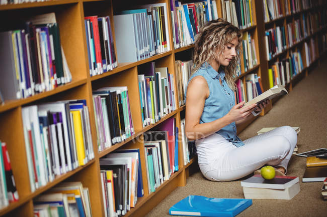 Жінка сидить і читає книгу в бібліотеці — стокове фото