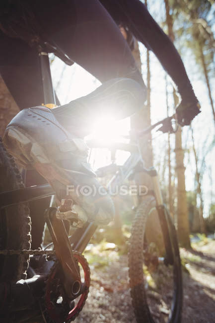 Baixa seção de mountain biker andando na estrada de terra na floresta — Fotografia de Stock
