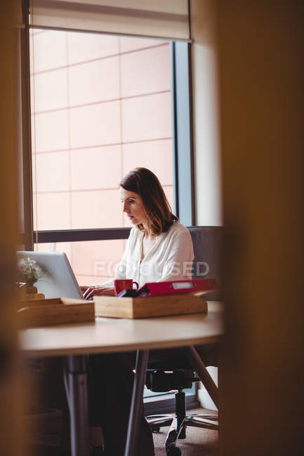 Бизнесвумен, работающая над ноутбуком в офисе — стоковое фото