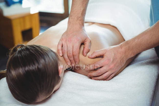 Physiotherapist giving physical therapy to shoulder of female patient in clinic — Stock Photo