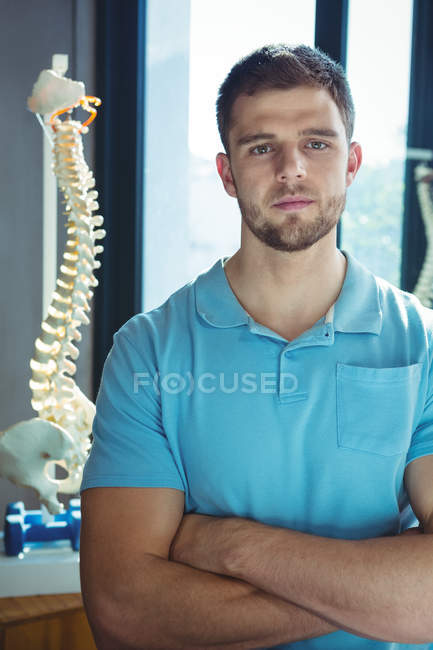 Портрет фізіотерапевта-чоловіка, що стоїть на руках, схрещених у клініці — стокове фото