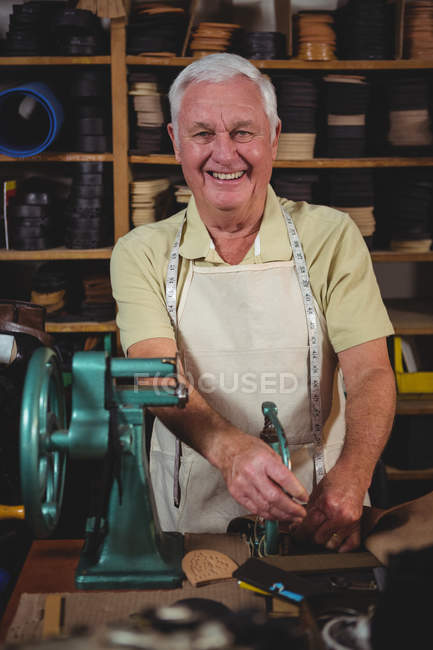 Cheerful shoemaker using sewing machine in workshop — Stock Photo