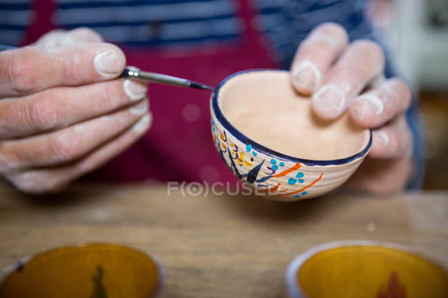 Close-up of potter painting on bowl in workshop — Stock Photo