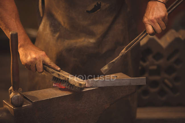Schmied arbeitet in Werkstatt an einer erhitzten Eisenstange — Stockfoto