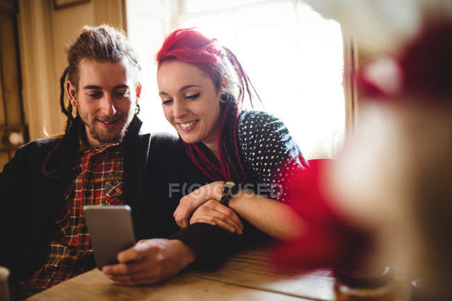 Alegre hipster casal usando telefone celular em casa — Fotografia de Stock