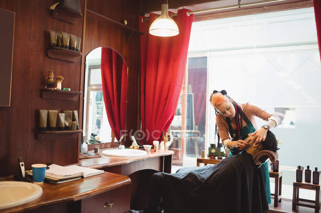 Man getting his beard shaved in a barber shop — Stock Photo