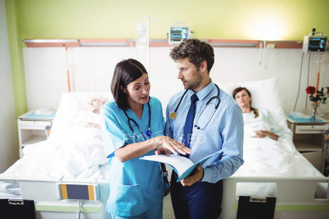 Médico interactuando con enfermera en la sala de hospital - foto de stock