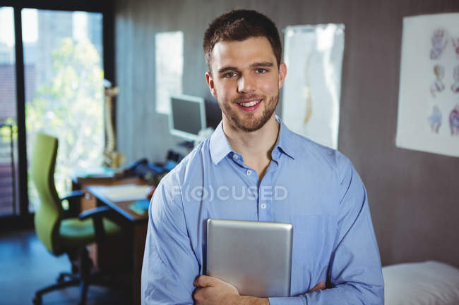 Retrato del fisioterapeuta masculino sosteniendo tableta digital en la clínica - foto de stock
