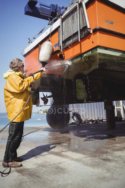 Man cleaning boat with pressure washer on sunny day — Stock Photo