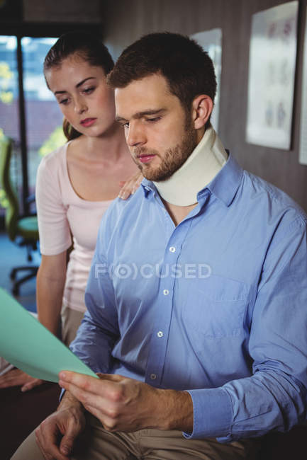 Patient and female physiotherapist looking at medical report in clinic — Stock Photo
