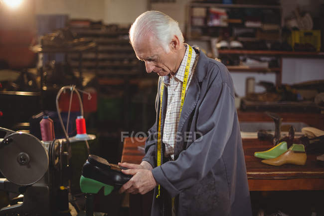 Zapatero reparando un zapato en taller - foto de stock