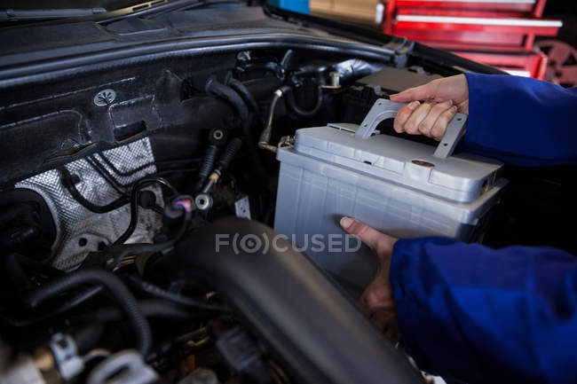 Geschnittenes Bild eines Mechanikers, der in der Werkstatt die Autobatterie aus dem Auto entfernt — Stockfoto