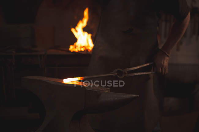 Коваль працює на нагрітому залізному стрижні в майстерні — стокове фото