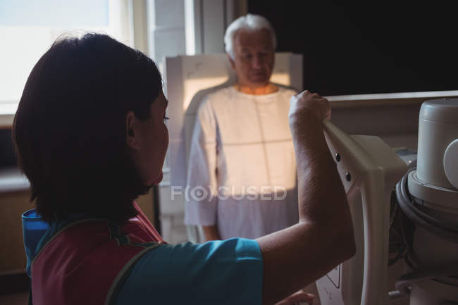 Female doctor setting up machine for x-ray senior patient at hospital — Stock Photo