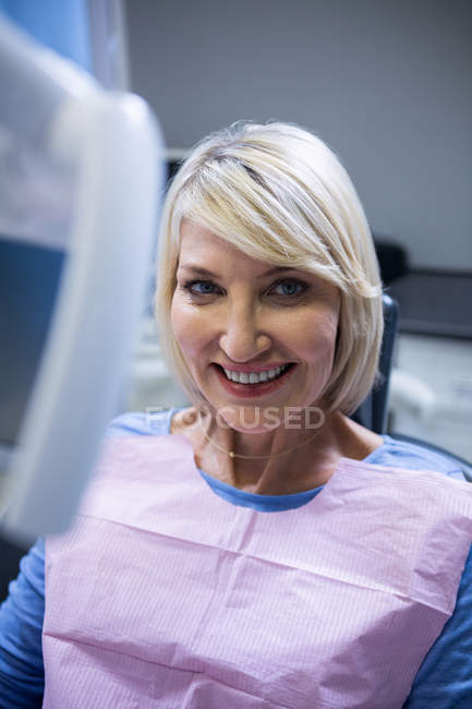 Улыбающийся пациент сидит на стоматологическом стуле в клинике — стоковое фото