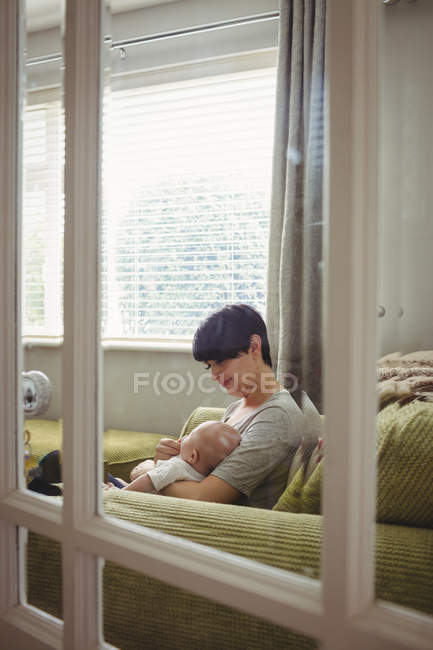 Матері годування її дитина у вітальні на дому — стокове фото