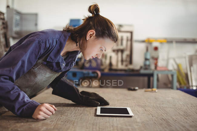 Schweißerin schaut in Werkstatt auf digitales Tablet — Stockfoto