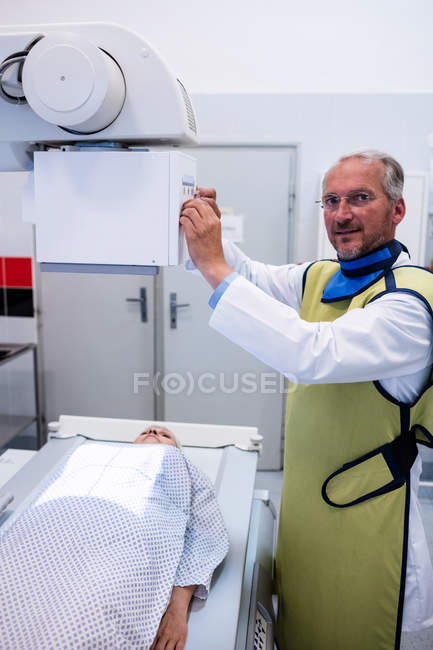 Врач-мужчина, использующий рентгеновский аппарат для обследования пациента в больнице — стоковое фото