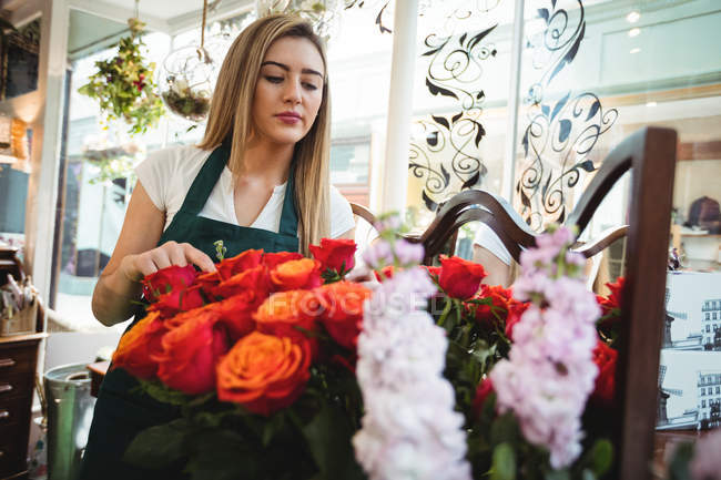 Fiorista femminile che organizza fiori nel negozio di fiori — Foto stock