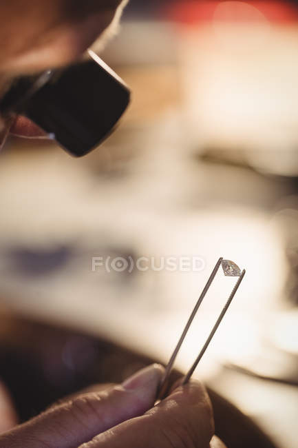 Goldsmith examinando el diamante a través de la lupa en taller - foto de stock