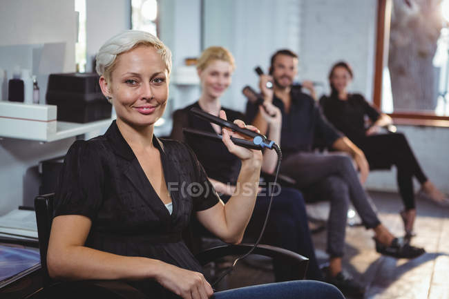 Retrato de cabeleireiros sorridentes sentados em cadeiras no salão — Fotografia de Stock