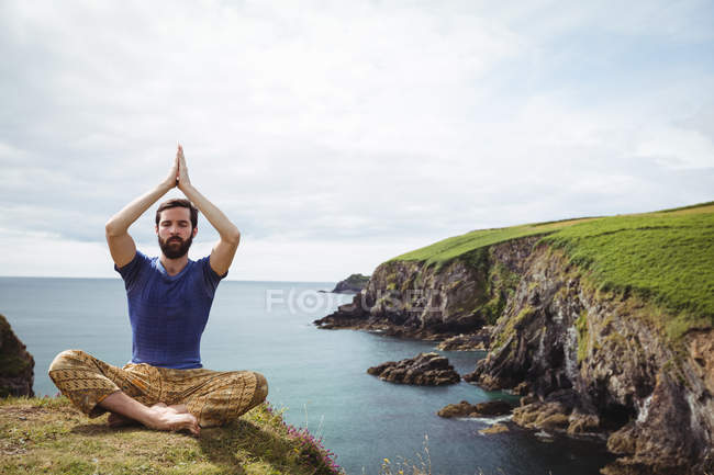 Homem realizando ioga no penhasco — Fotografia de Stock