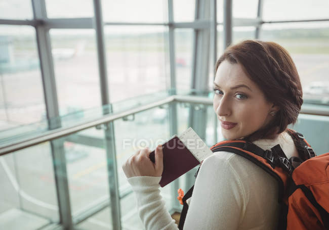 Портрет жінки з паспортом, що стоїть в зоні очікування в терміналі аеропорту — стокове фото