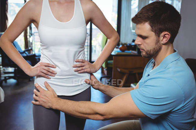 Physiotherapist correcting position of female patient in clinic — Stock Photo