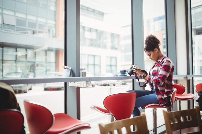Junge Frau hält Kamera während sie im Restaurant sitzt — Stockfoto