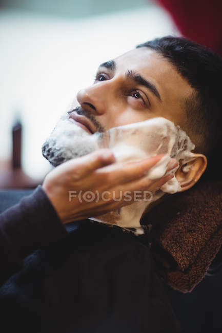 Man getting his beard shaved in barber shop — Stock Photo