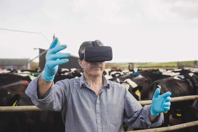 Travailleur agricole portant simulateur de réalité virtuelle par une clôture contre le ciel — Photo de stock