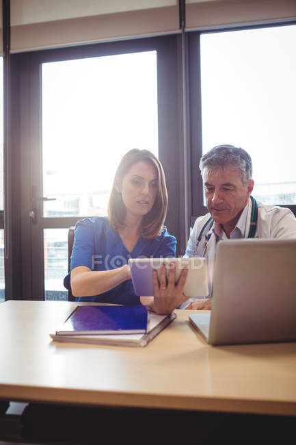 Doctor discussing with nurse over digital tablet at hospital — Stock Photo