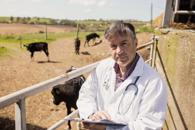 Porträt eines Tierarztes mit Klemmbrett am Zaun an einem sonnigen Tag — Stockfoto