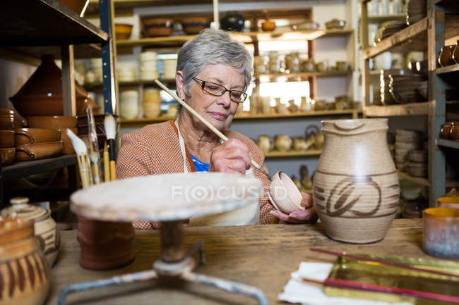 Pittura femminile su ciotola in laboratorio di ceramica — Foto stock