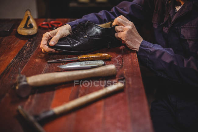 Mittelteil eines männlichen Schuhmachers, der in der Werkstatt einen Schuh repariert — Stockfoto