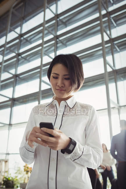 Pasajera asiática usando teléfono móvil en terminal de aeropuerto - foto de stock