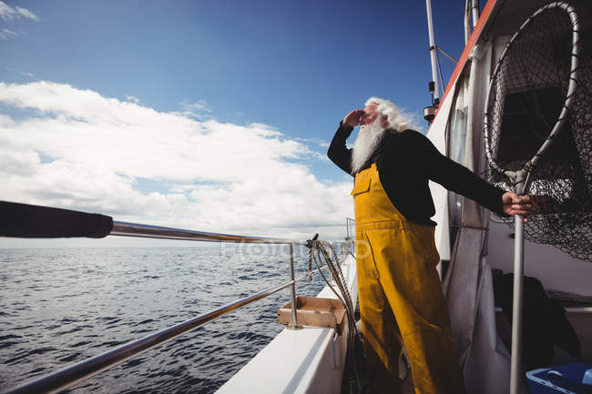 Visão de baixo ângulo do pescador segurando rede de pesca e olhando para a vista de barco — Fotografia de Stock