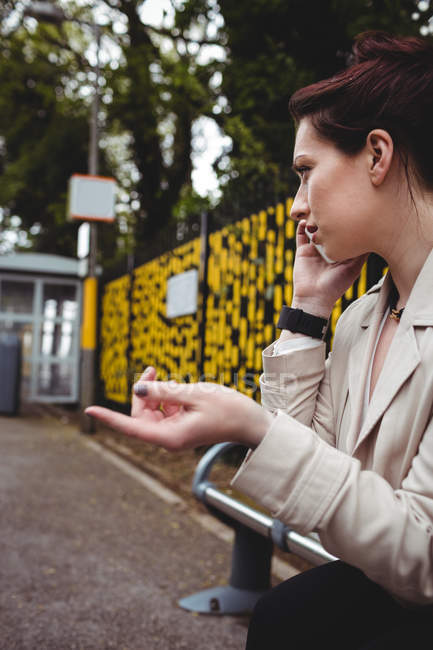 Pretty woman talking on phone at railroad station — Stock Photo