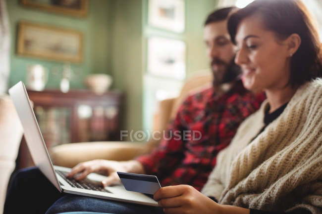 Couple shopping en ligne sur ordinateur portable dans le salon à la maison — Photo de stock