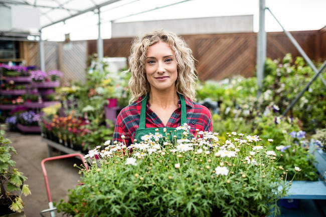 Портрет женщины-флористки, держащей поднос с растениями в садовом центре — стоковое фото