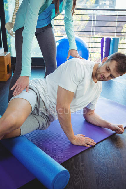 Fisioterapeuta feminina dando fisioterapia ao joelho do paciente masculino na clínica — Fotografia de Stock