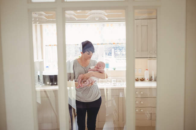 Мать играла со своим малышом на кухне дома — стоковое фото